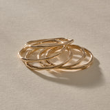 Five Nova gold stacking rings resting together, showing their organic, hand-formed shapes.