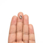 The loose pear rose cut diamond resting on fingertips to show its size.