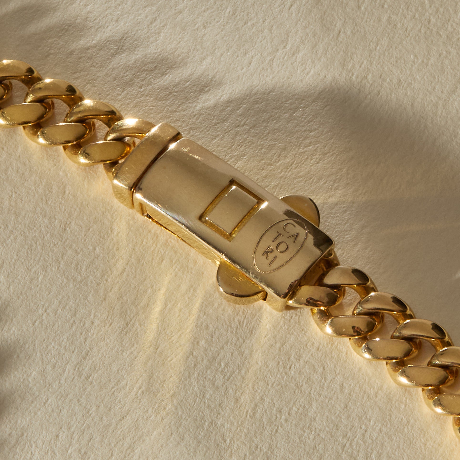 Close view of the engraved box clasp on the Oro Sagrado Cuban Link Bracelet in 14k gold.