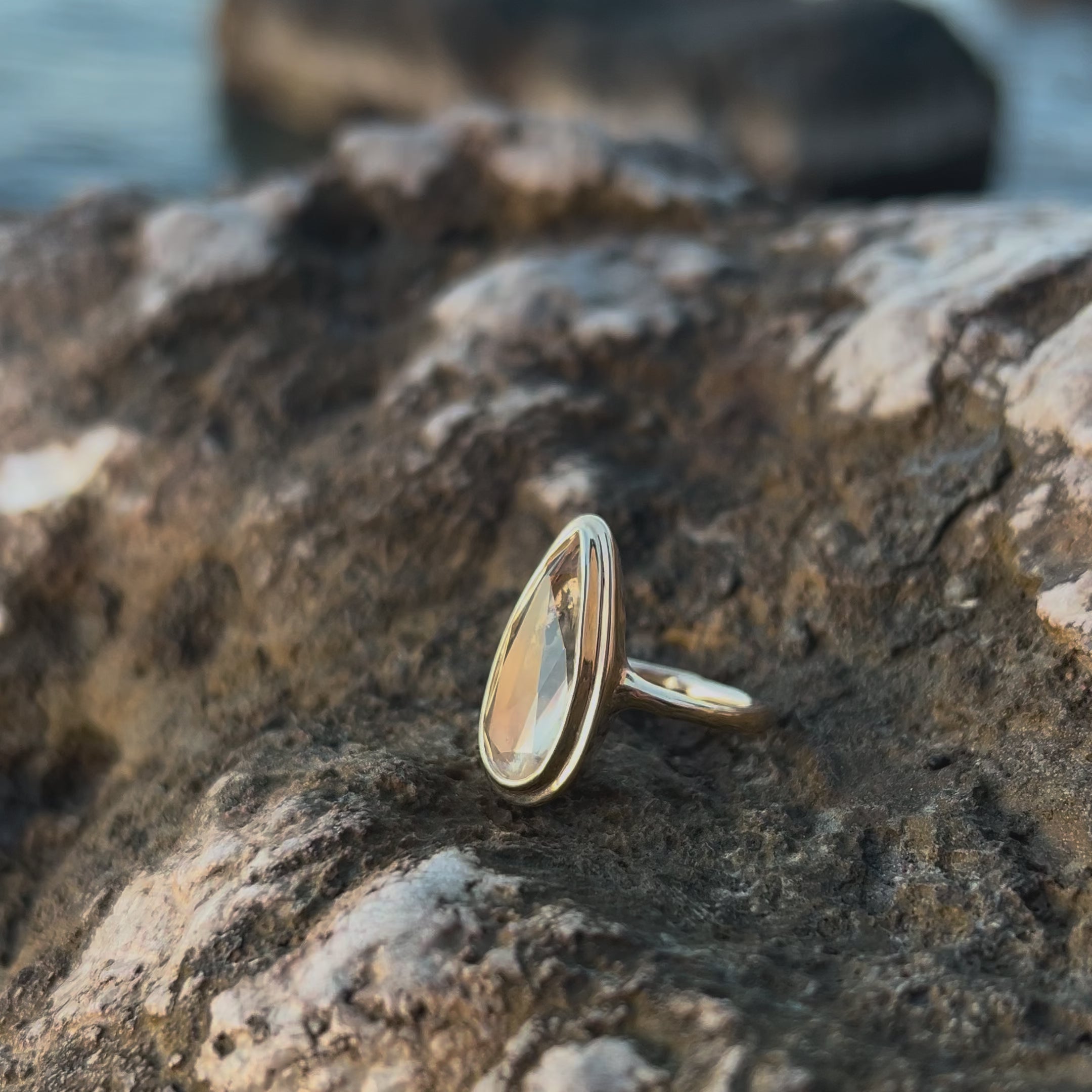 The Solaria heliodor ring resting on a sunlit rock outdoors, the golden beryl sparkling as the light moves.