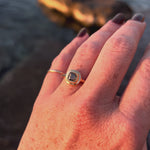 The Ambre Ring worn on the hand by firelight, its champagne diamond catching the warm glow.