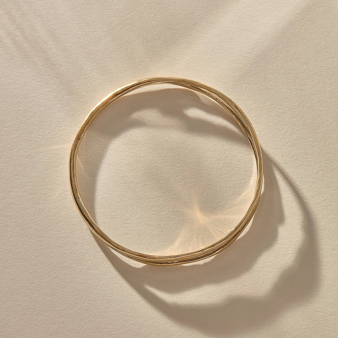 Reverie Organic Bangle in gold from above, showing its flowing, river-like shape.