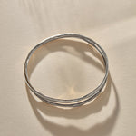 Reverie Organic Bangle in sterling silver from above in soft shadow, showing the split band.