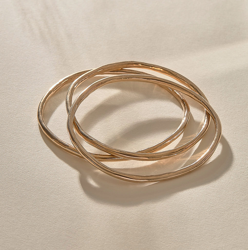 Set of 3 Rustic Bangles in bronze at an angle, showing their weight and organic shape.