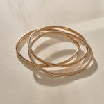 Set of 3 Rustic Bangles in bronze at an angle, showing their weight and organic shape.