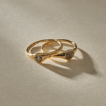 The Selkie Stack II, two one of a kind natural grey diamond rings in organic 14k recycled gold settings, resting together.