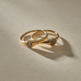 The Selkie Stack II, two one of a kind natural grey diamond rings in organic 14k recycled gold settings, resting together.
