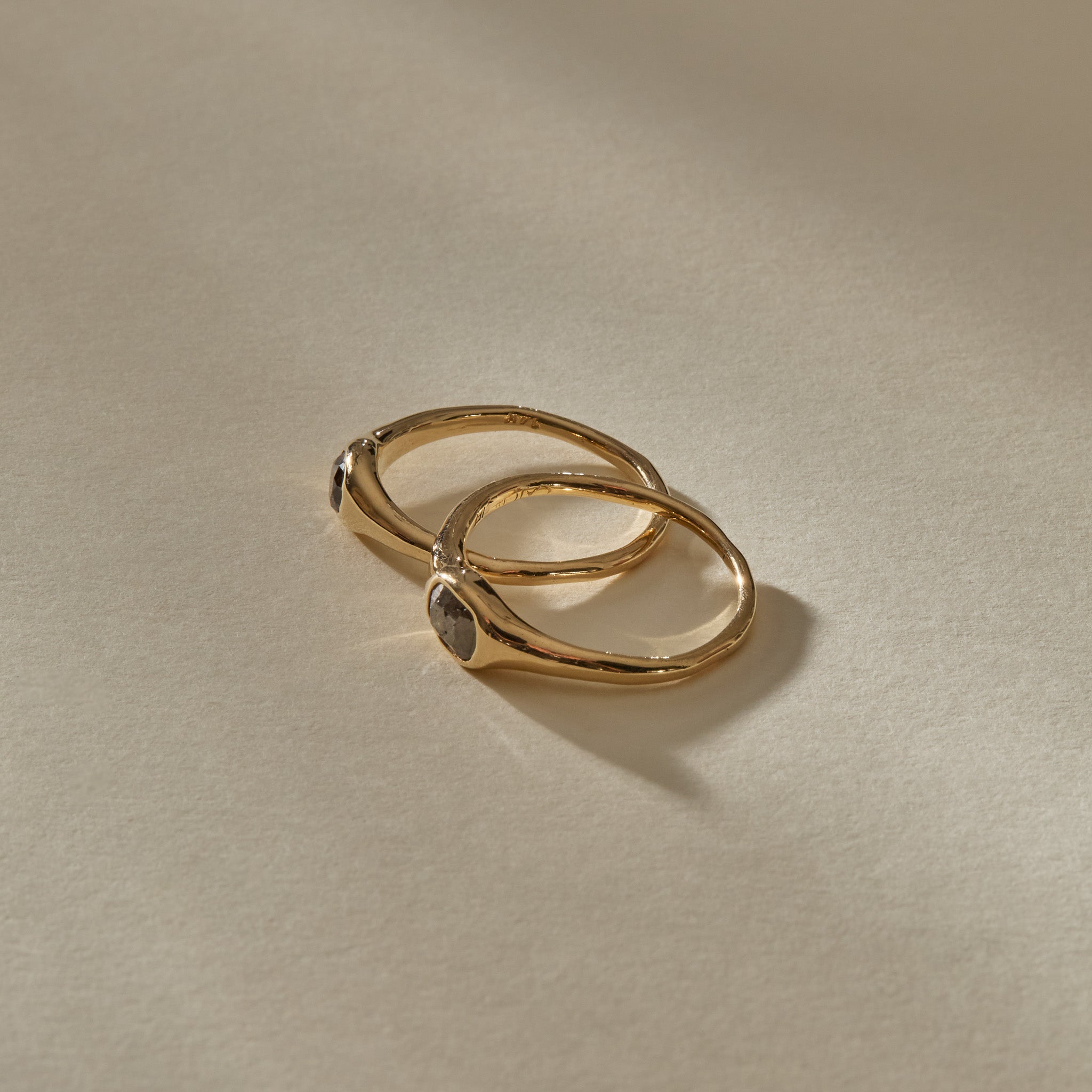 Selkie Stack II rings at an angle, with the grey diamonds set into the sculpted gold faces.