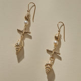 Sereia Shell and Pearl Chandelier Earrings in gold laid at an angle, the pearls catching the light.