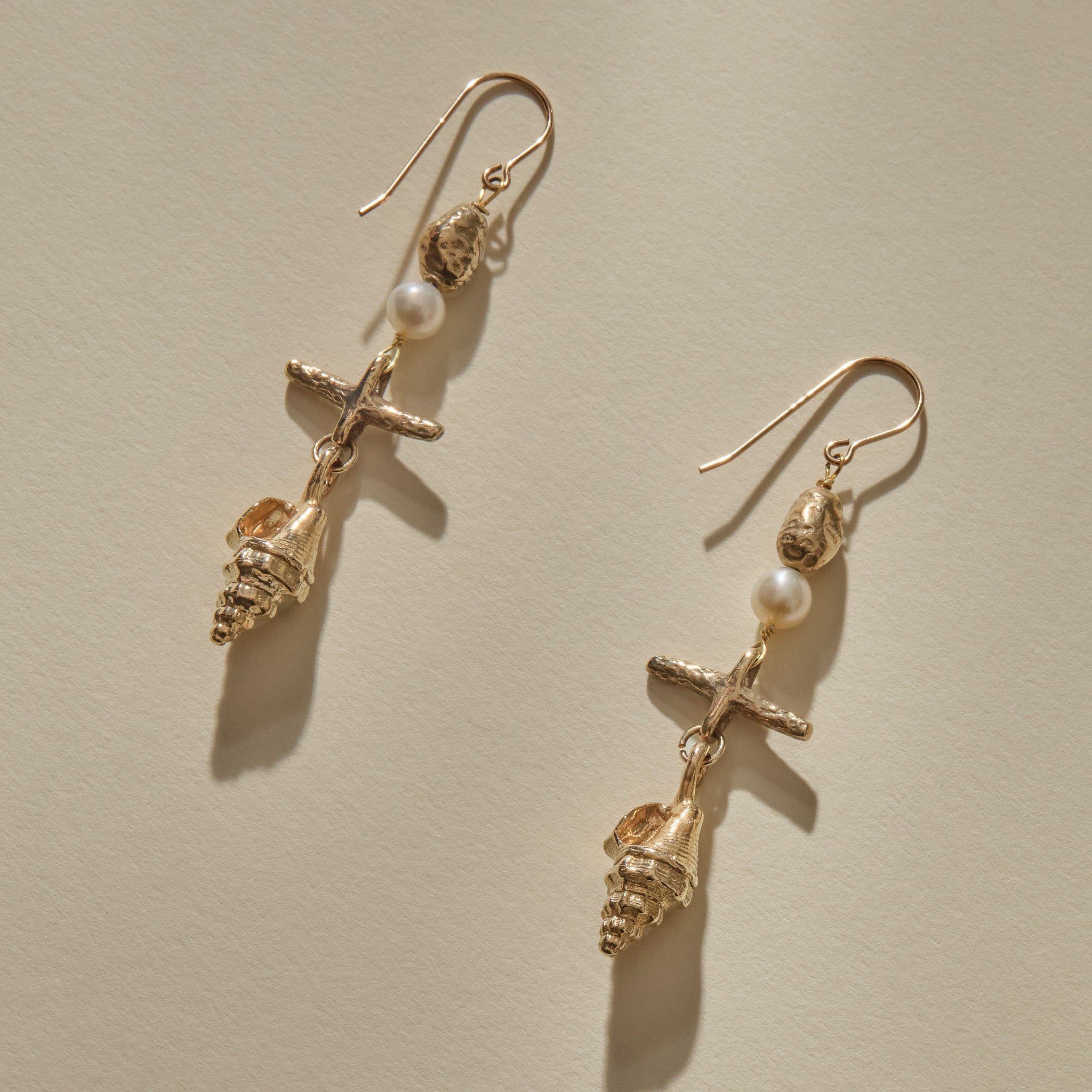 Sereia Shell and Pearl Chandelier Earrings in solid recycled gold, a pearl and cast spiral seashell drop on gold hooks.