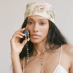 Sereia Shell and Pearl Chandelier Earrings worn by a model in a floral headscarf.