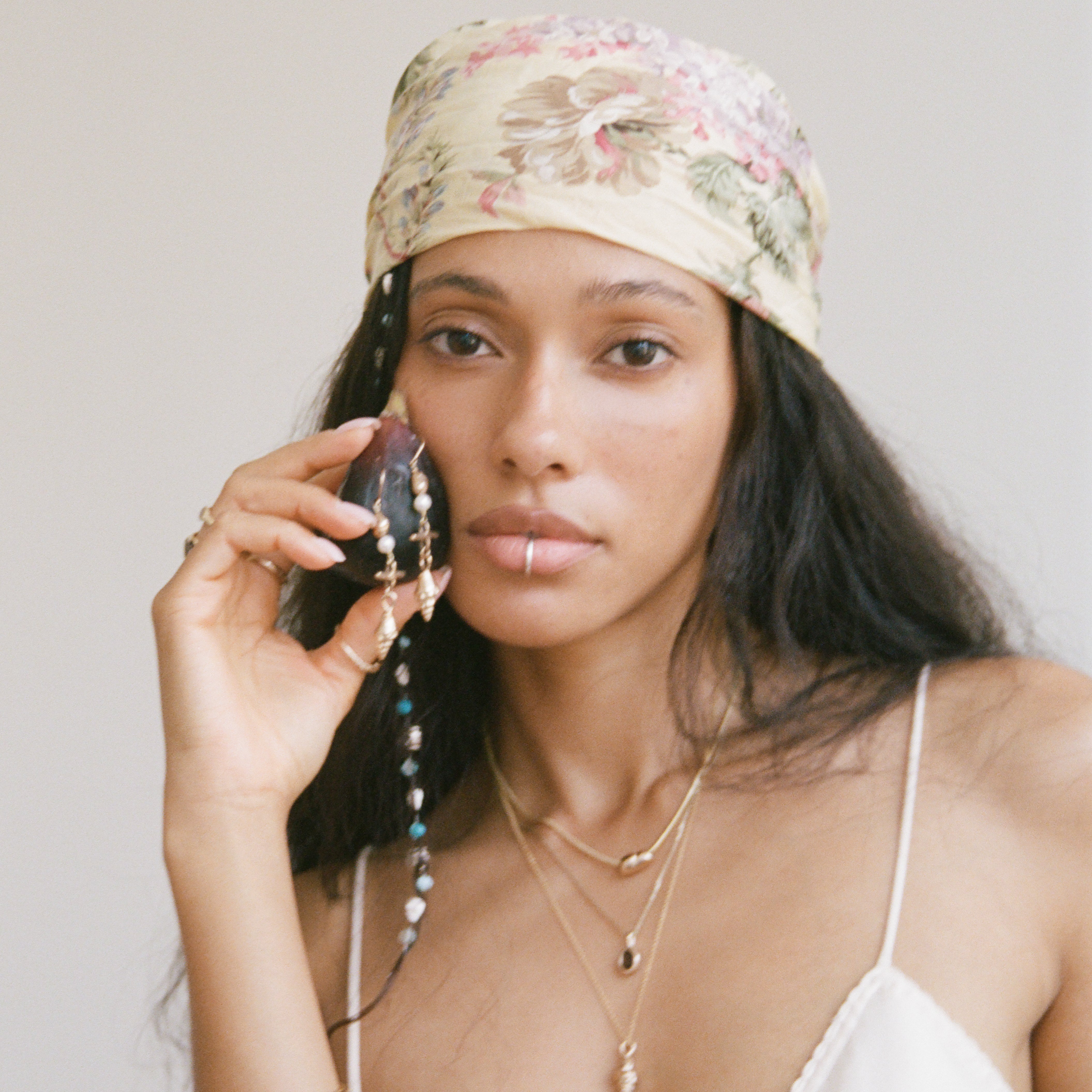 Sereia Shell and Pearl Chandelier Earrings worn by a model in a floral headscarf.