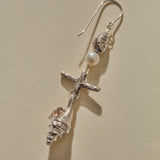 Close view of a Sereia Shell and Pearl Chandelier Earring in sterling silver, the pearl above the ridged spiral shell.