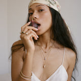Sereia Spiral Shell Necklace in gold worn by a model in a headscarf, layered with fine chains.