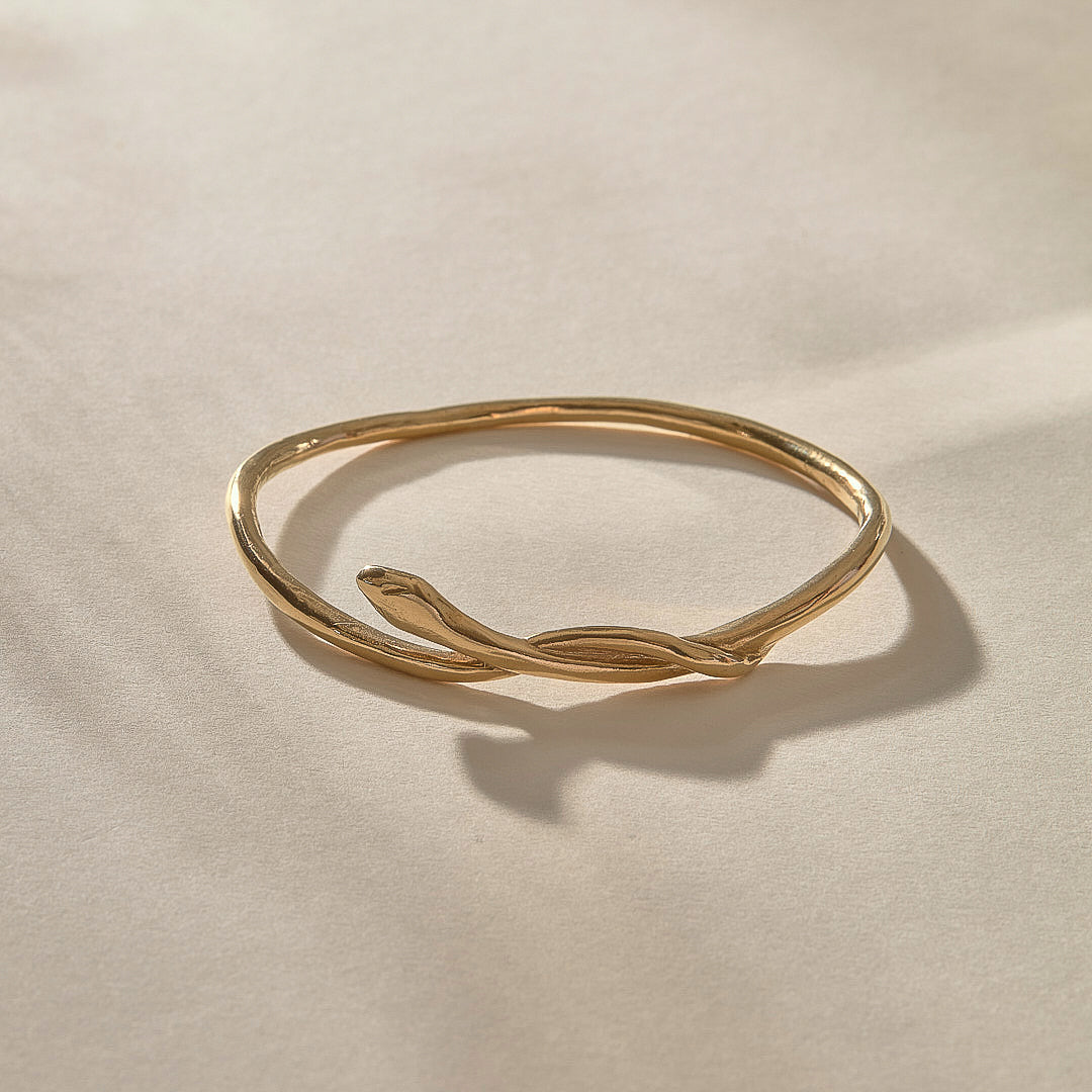 Serpent Snake Bangle in gold from the side, with the snake head resting on the band.