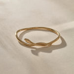 Serpent Snake Bangle in gold from the side, with the snake head resting on the band.