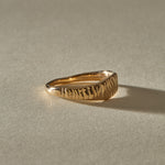 Smoke Ring in solid recycled gold at an angle, with the carved face rising from the tapered band.
