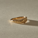 Smoke Ring in solid recycled gold at an angle, with the carved face rising from the tapered band.