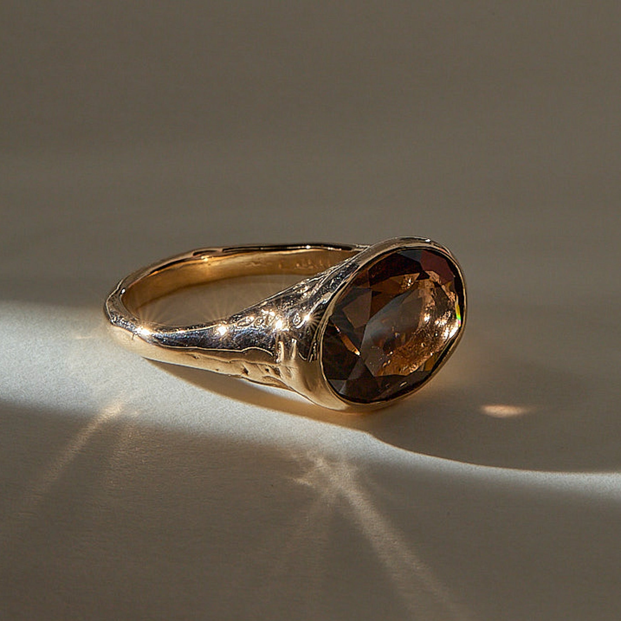 Smoky Quartz Signet Ring in recycled bronze, angled view with light catching the faceted stone