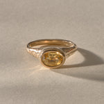Solara Citrine Signet Ring in solid recycled gold, a faceted oval golden citrine in a smooth bezel on an organically textured band, in warm sunlight.