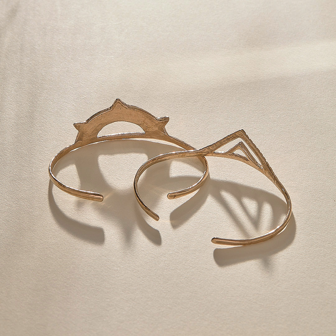 Sunkeeper and Pyramids cuffs in bronze from above, the sun and pyramid faces side by side.