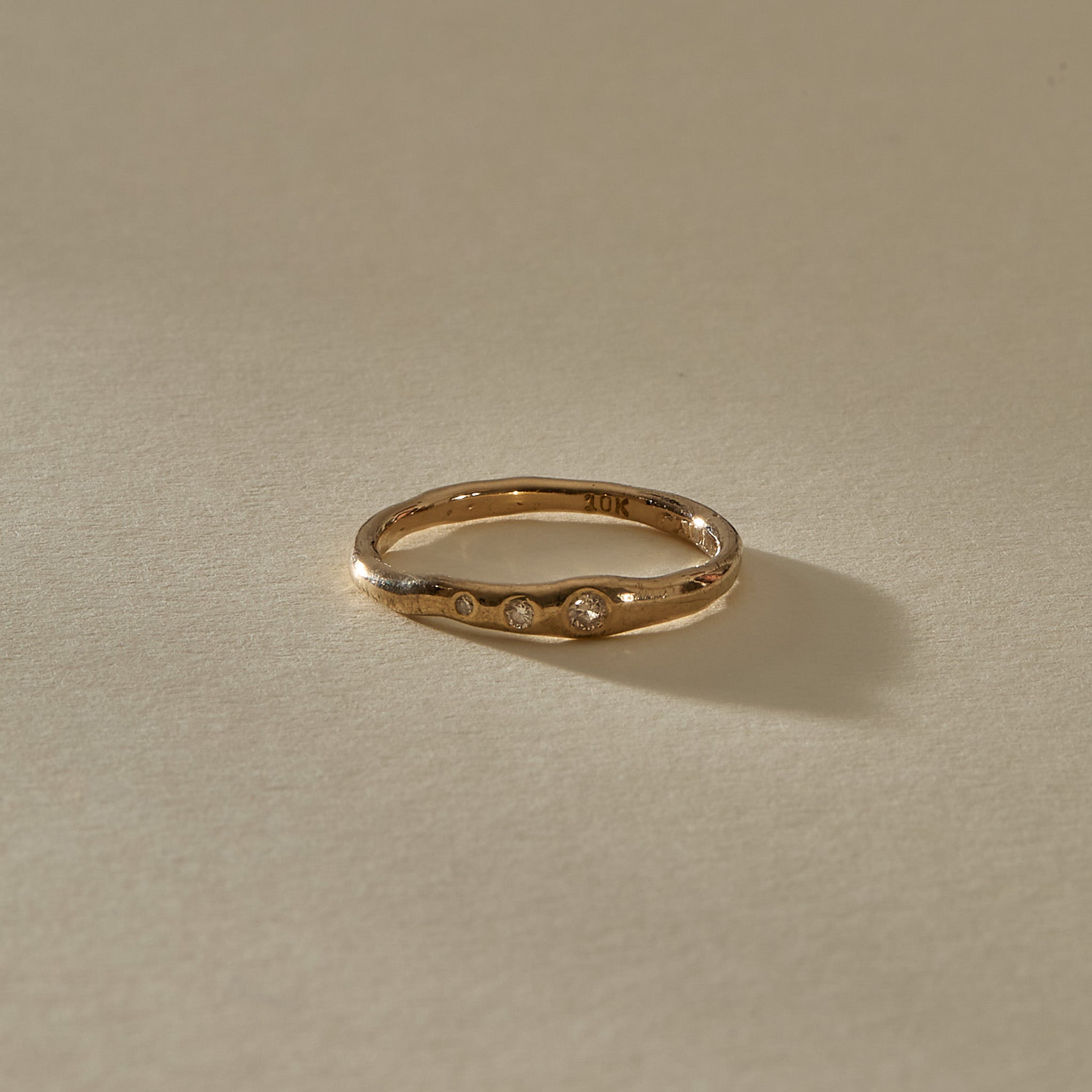 Vida Diamond Ring from the front, showing three tiny champagne diamonds set along the curved gold band.