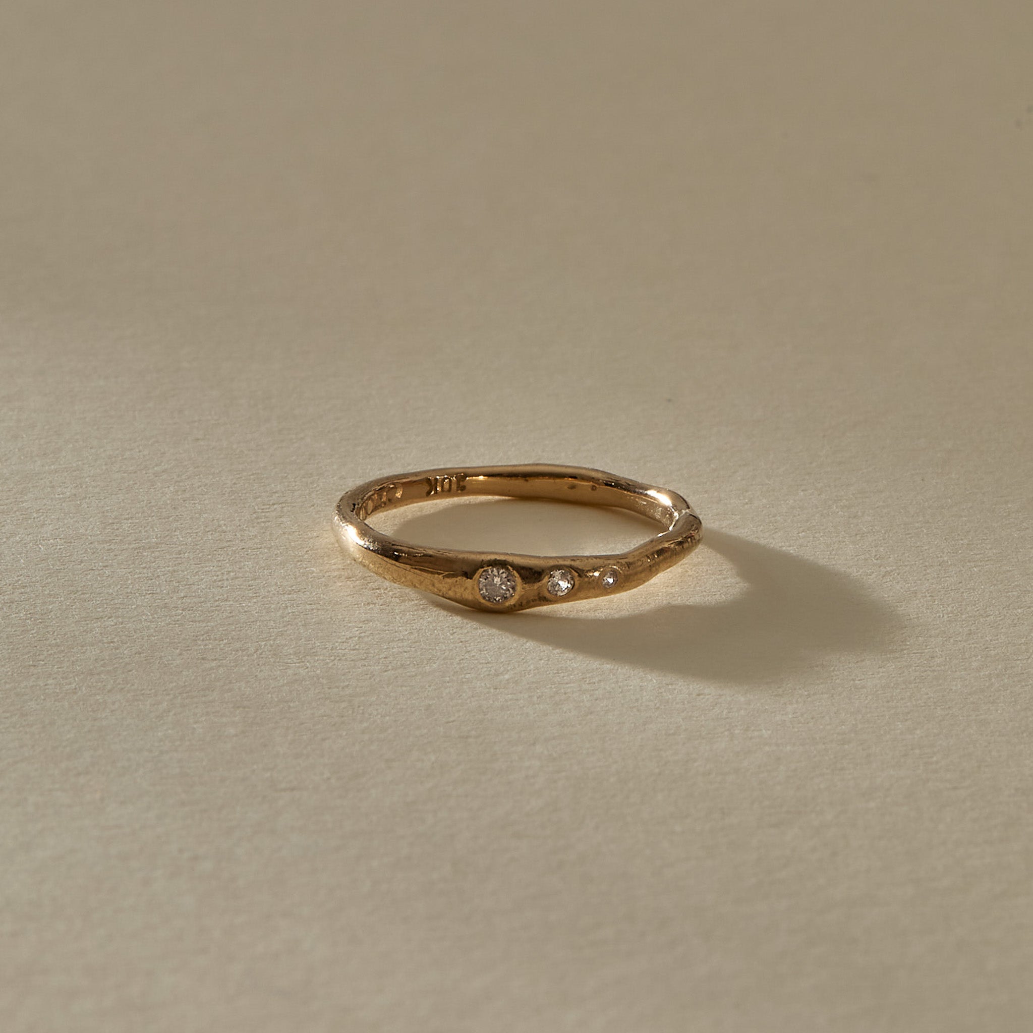 Vida Diamond Ring, a delicate organic band in solid recycled gold set with three graduated champagne diamonds, in soft sunlight.