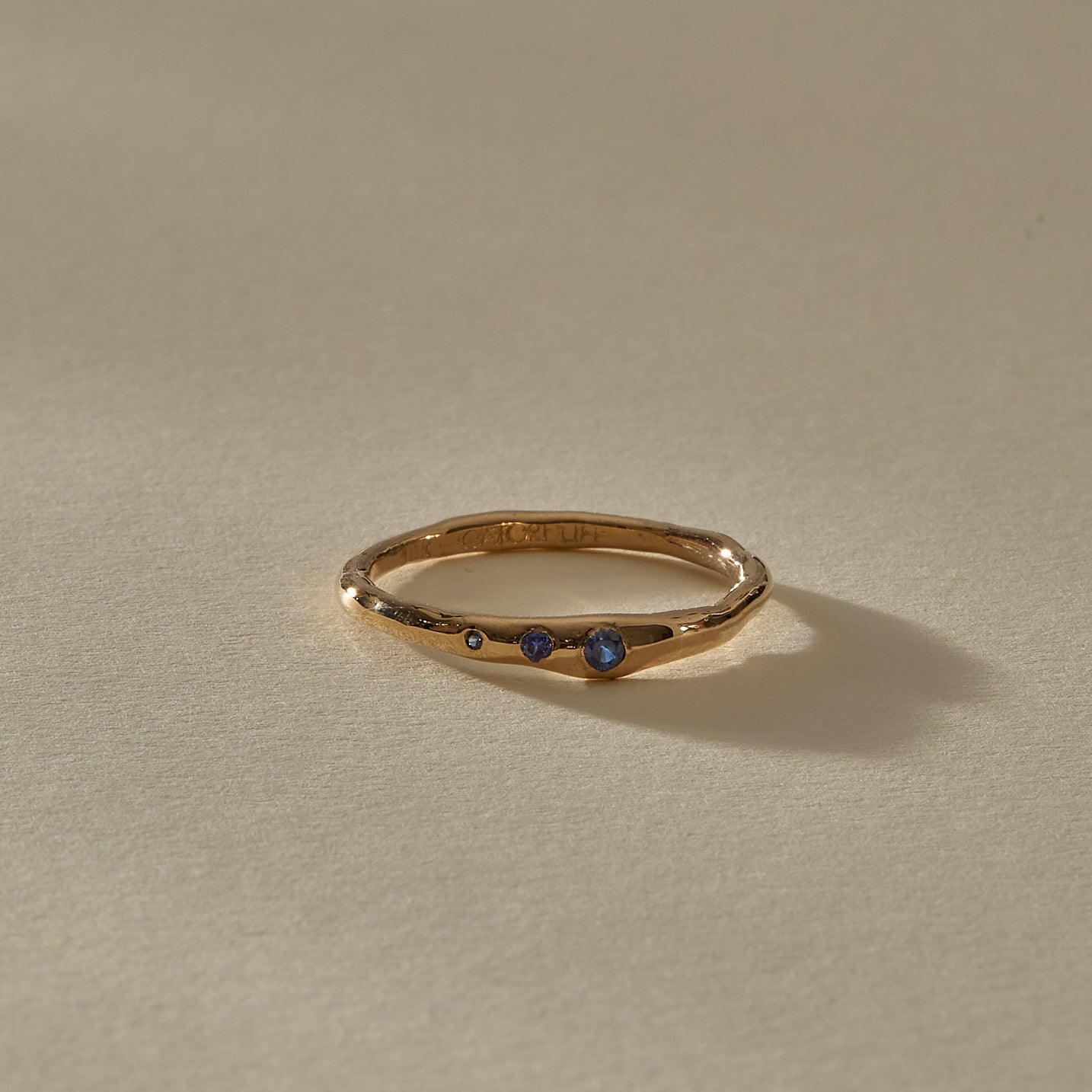 Vida Sapphire Ring at an angle, a thin organic gold band with a single sapphire showing at the front.