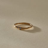 Vida Sapphire Ring from the front, showing three tiny blue sapphires set along the gently curved gold band.