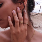 Model with her hand to her face wearing the Devotions Wave Ring and other stacking rings.