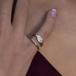 Hand resting on burgundy fabric wearing the Evil Eye Protection Ring stacked with a slim band.