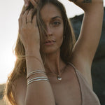 Model with her hand in her hair wearing stacked Reverie Organic Bangles.