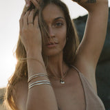 Model with her hand in her hair wearing stacked Reverie Organic Bangles.