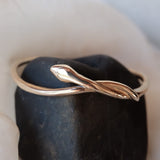 Serpent Snake Bangle in bronze displayed on a dark stone.
