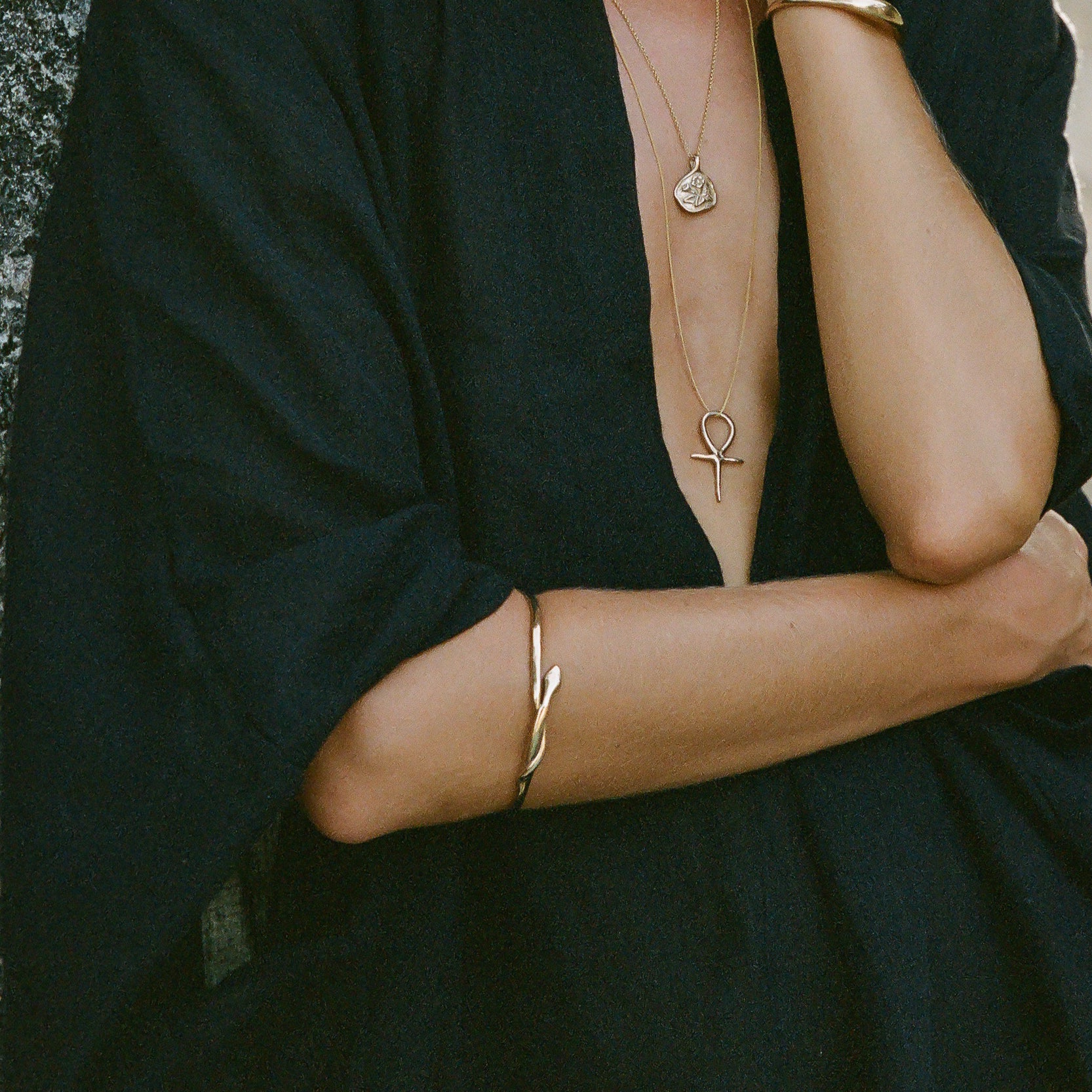 Serpent Snake Bangle worn on the arm of a model in a black wrap dress with layered necklaces.