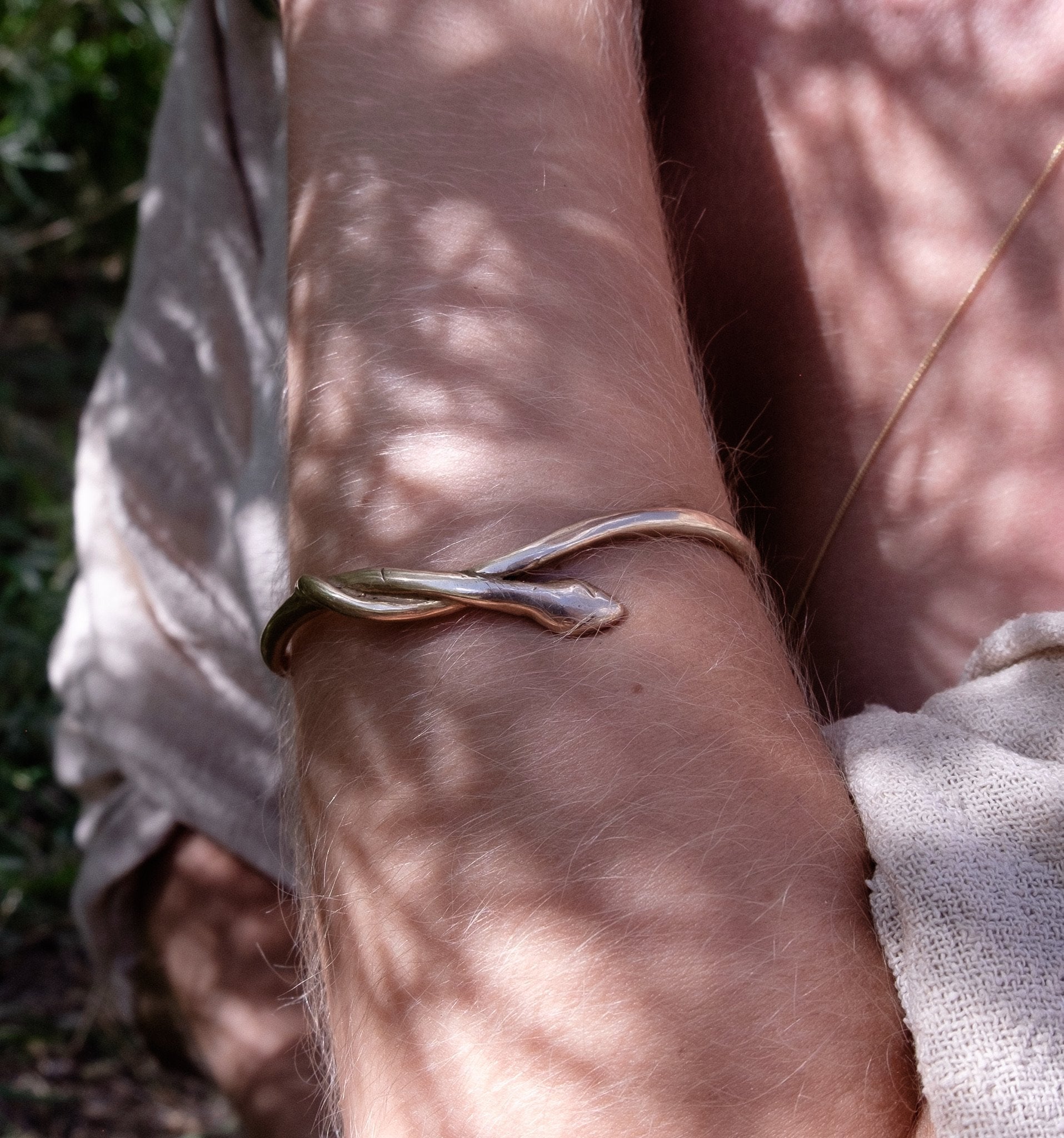 Serpent Snake Bangle worn on the wrist in dappled sunlight.