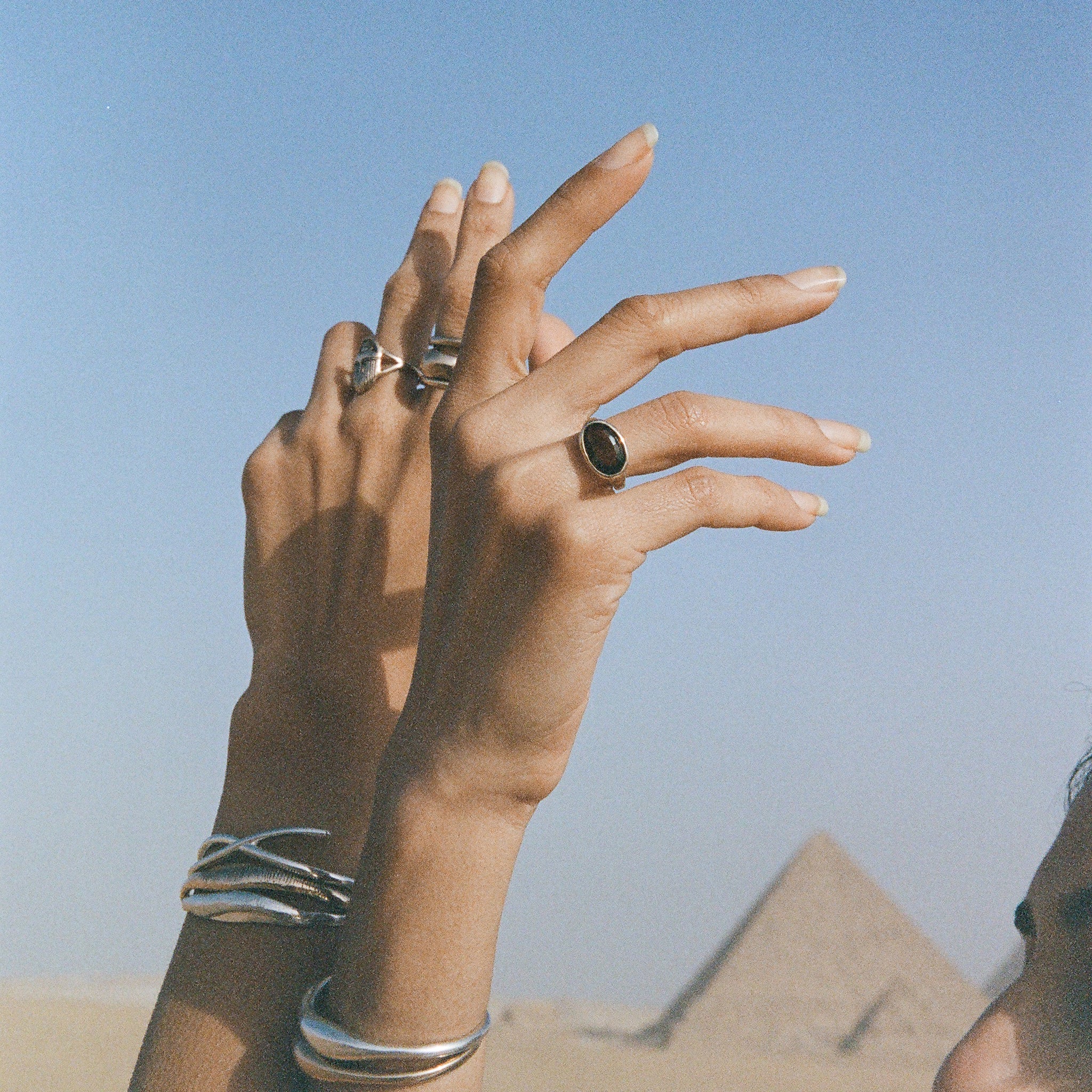Hands raised in front of the pyramids of Giza, wearing the Smoky Quartz Signet Ring and stacked Catori Life rings