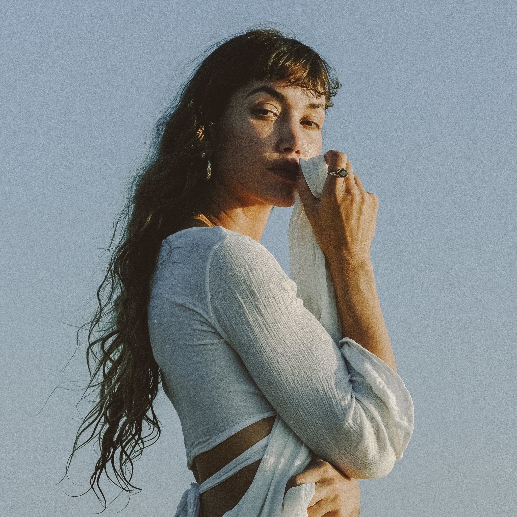 Model in a white top against a blue sky, wearing the Smoky Quartz Signet Ring