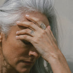 Silver-haired model with her hand at her brow, wearing the Venus Signet Ring.