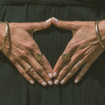 Model's hands forming a triangle, wearing the Venus Signet Ring and other rings.