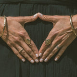 Model's hands forming a triangle, wearing the Venus Signet Ring and other rings.