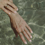 Hand resting in clear water, wearing stacked Wabi Rings