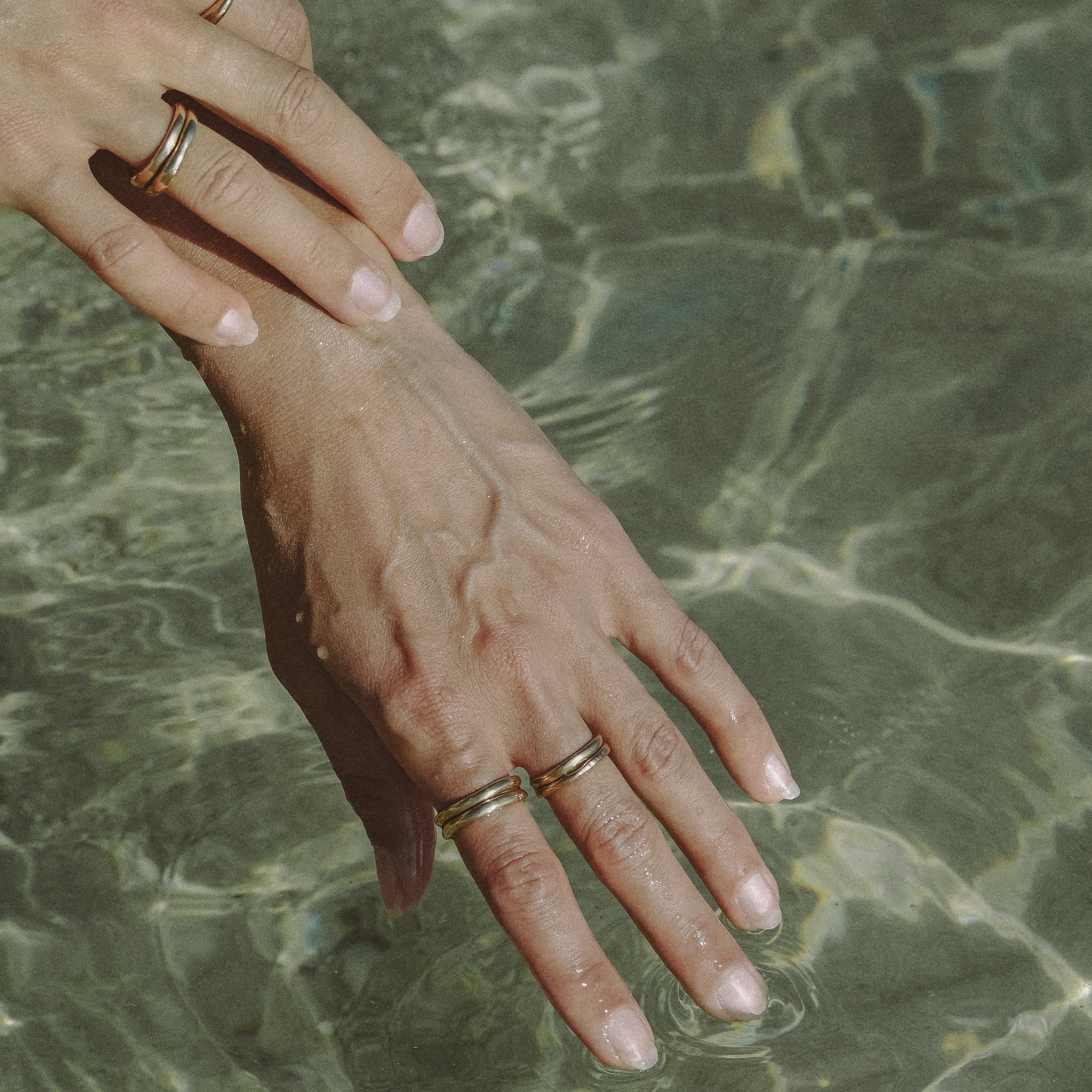 Hand resting in clear water, wearing stacked Wabi Rings