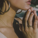 Model with her fingertips at her chin and hoop earrings, wearing stacked Wabi Rings