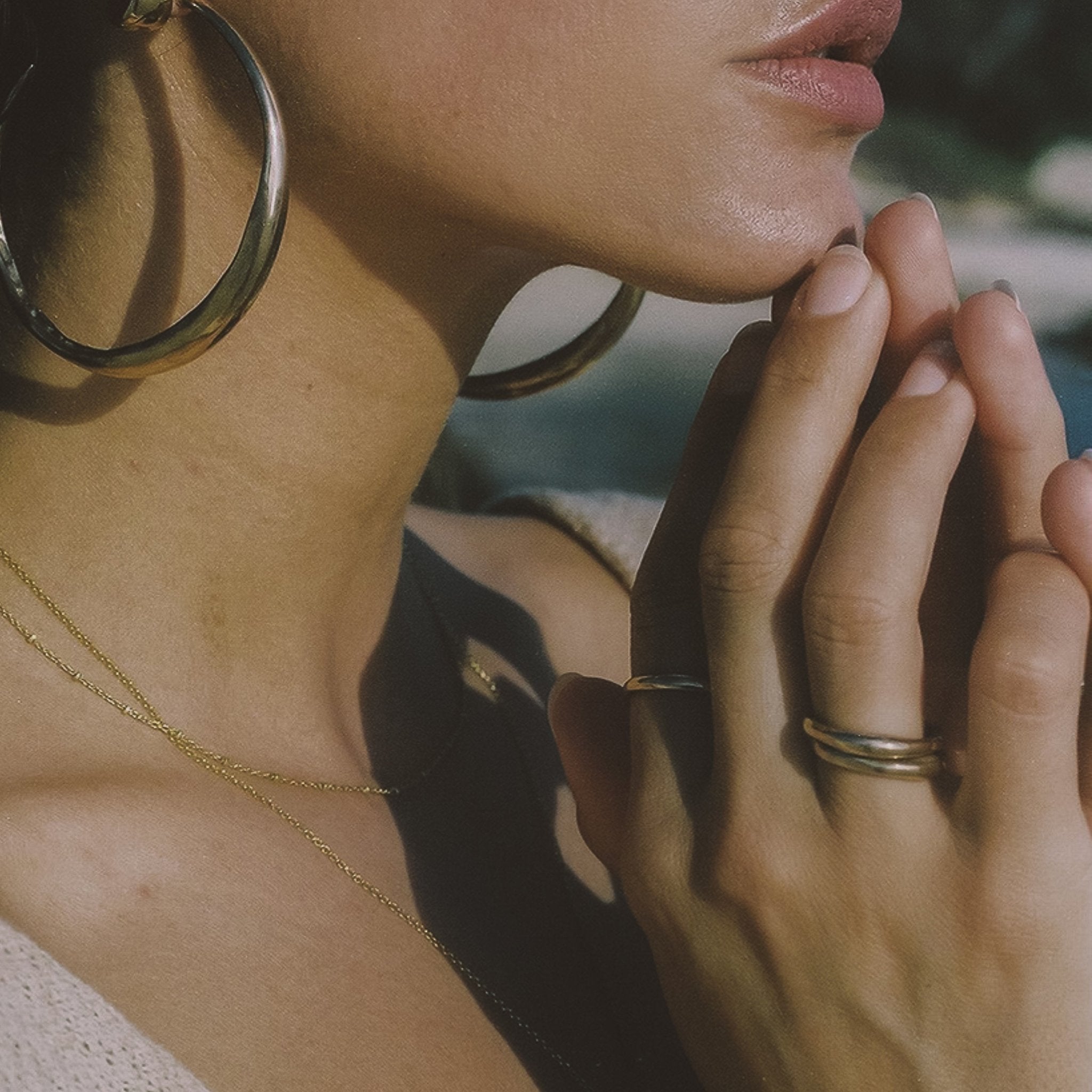 Model with her fingertips at her chin and hoop earrings, wearing stacked Wabi Rings