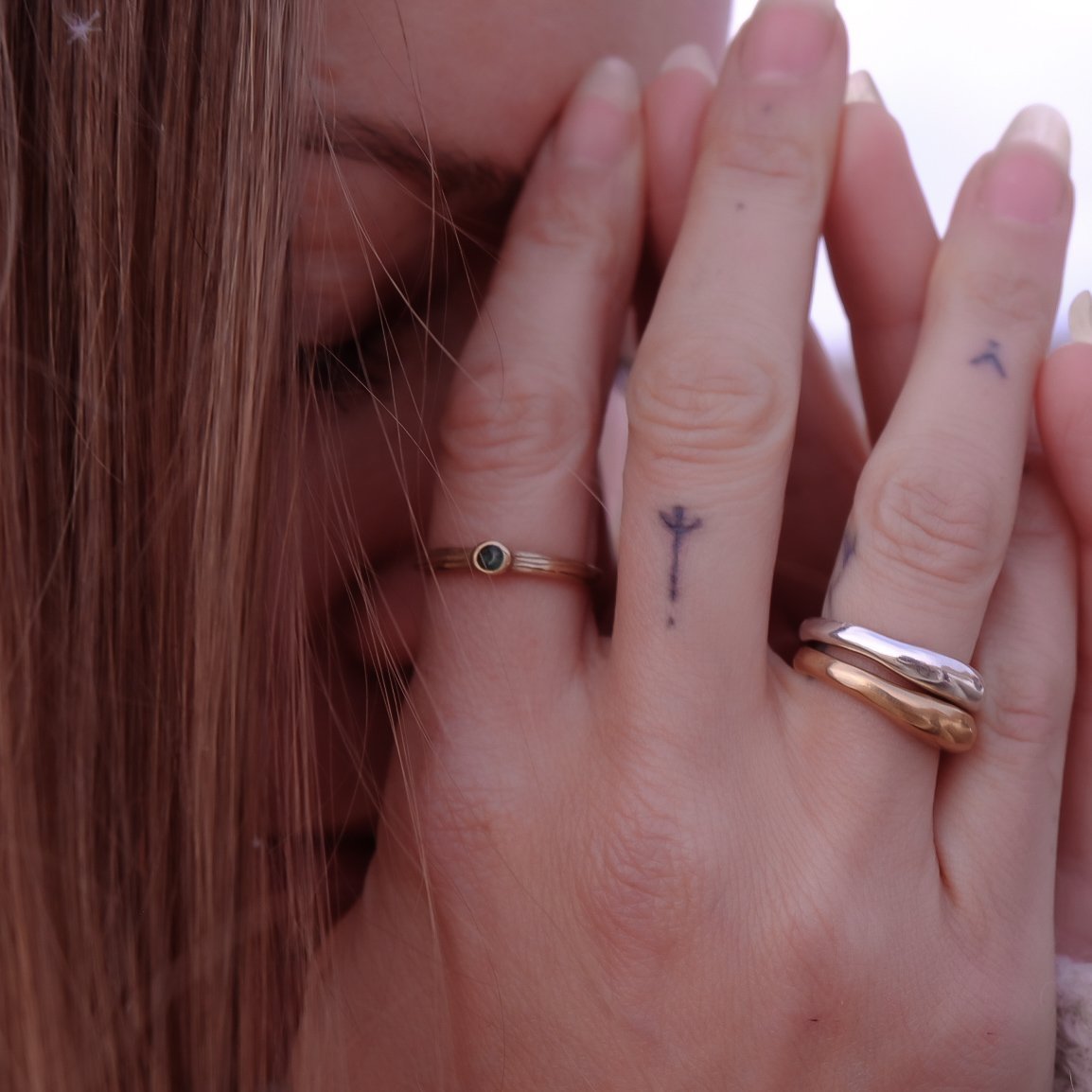 Model with her hands at her face, wearing the Wabi Ring stacked with Catori Life rings