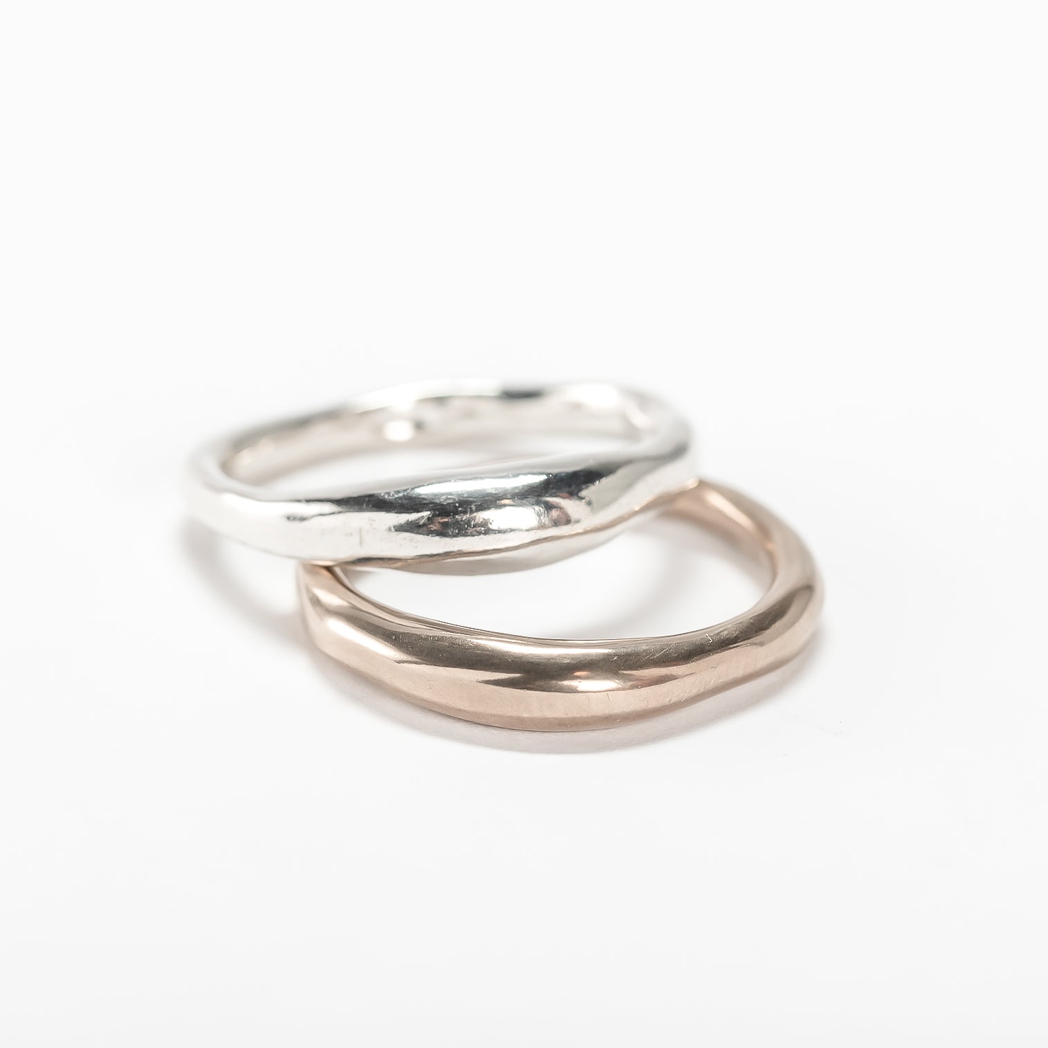 Two Wabi Rings stacked, one in sterling silver and one in warm-toned metal, on a white background